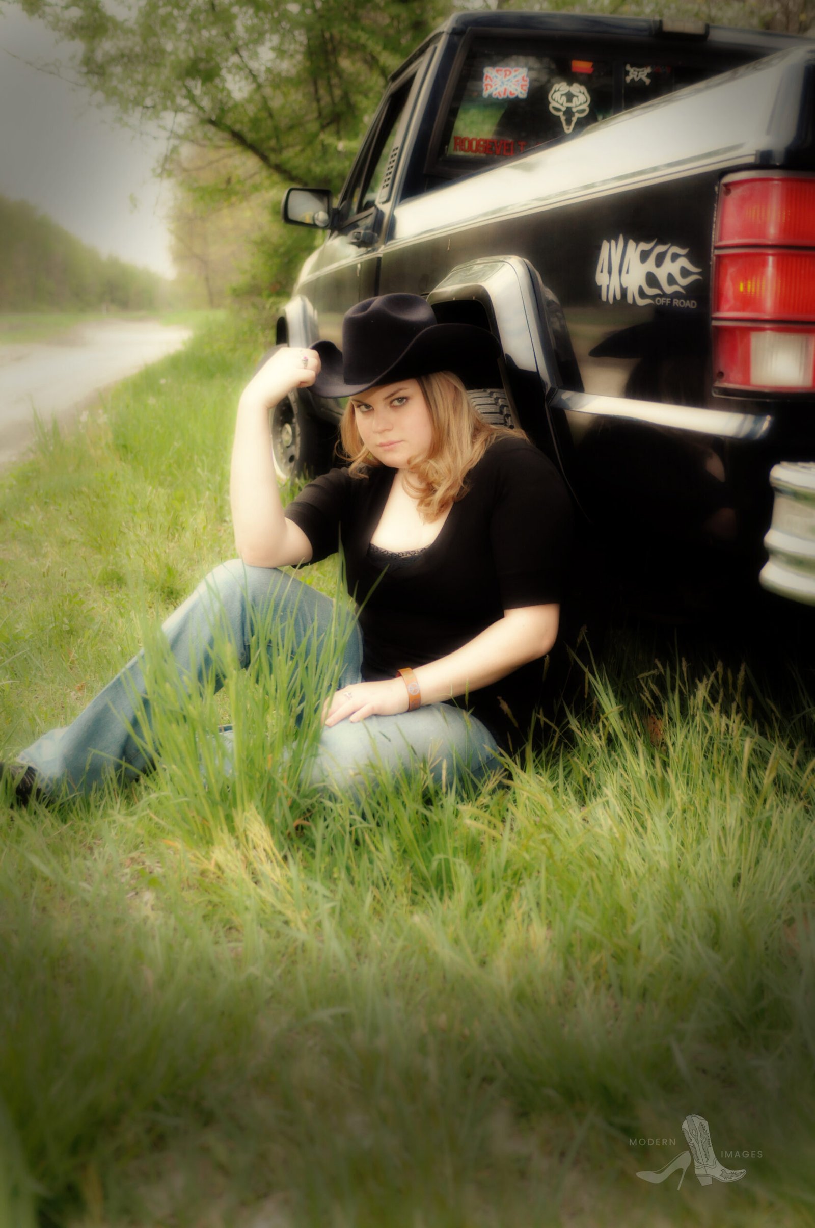 Western-inspired high school senior girl sitting against a vintage Ford truck, wearing a black cowboy hat and boots—captured in a rustic, country-style senior portrait session by a Columbus, Ohio senior photographer.